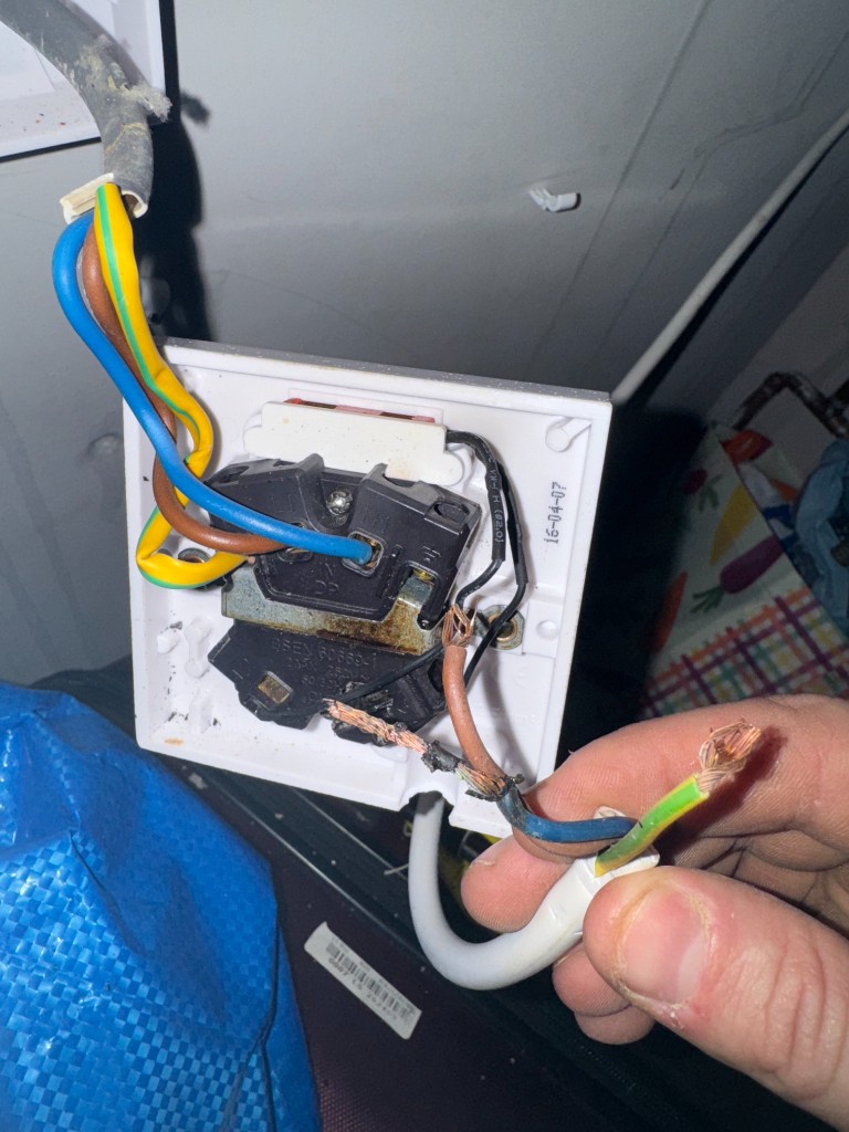 CoverEstate electrician repairing exposed wiring at a damaged socket outlet
